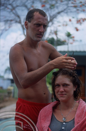 T04141. Phil cutting Alex's hair. Ivans backpackers. Darwin. Northern Territory. Australia.  September 1992