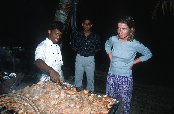 T14415. Lynn watching the chef cooking meat for the Sunday barbecue alfresco. Goyambokka. Tangalle. Sr Lanka. 22.12.02.