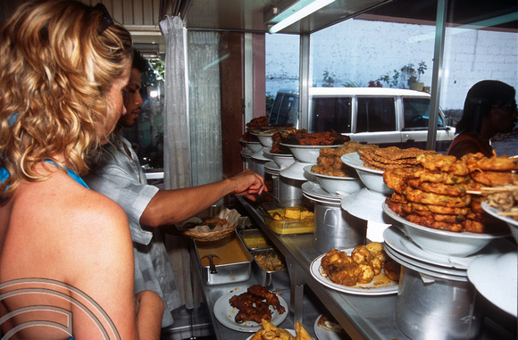 T015981. Lynn choosing dishes at a Padang food stall. Ubud. Bali. Indonesia. 20th September 2003