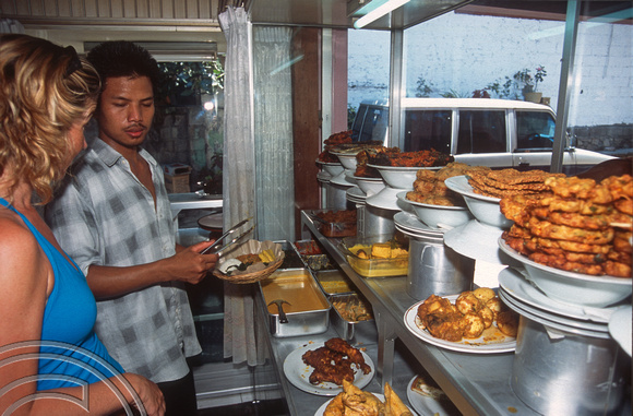 T015982. Lynn choosing dishes at a Padang food stall. Ubud. Bali. Indonesia. 20th September 2003