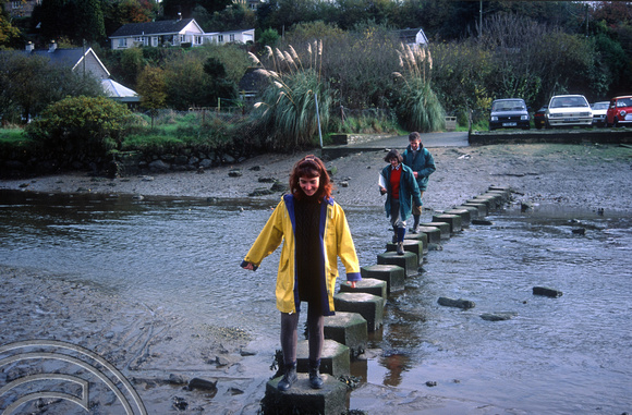 10th November 1995. Lynn on stepping stones in yellow mac. Cornwall