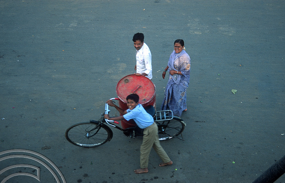 T03103. Moving a 40 gallon oil drum by bicycle. Mysore. Karnataka. India. December 1991.