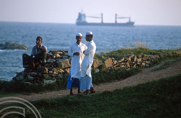 T15125. Yong Moslem men watch the world go by from the fort ramparts. Old town. Galle. Sri Lanka. 13.01.2002