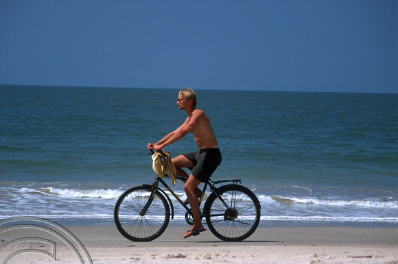 T9623. Man cycling on the beach. Colva. Goa. India. 09.02.2000