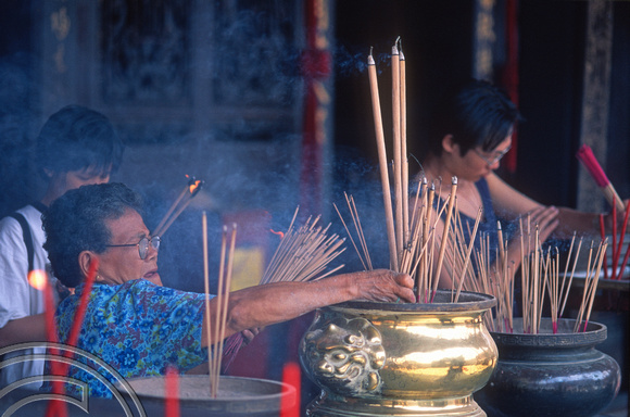T7383. Lighting joss sticks in a Chinese Temple. Melaka. Malaysia.  June 1998