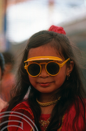 T9790. Girl with sunglasses at a wedding procession. Bhavnagar. Gujarat. India. 19th February 2000